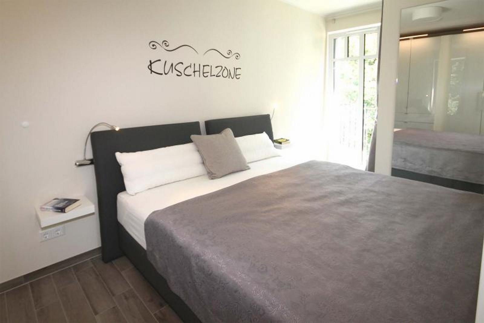 Schlafzimmer mit Bett, Wanddekoration und Fenster zur Aussicht.