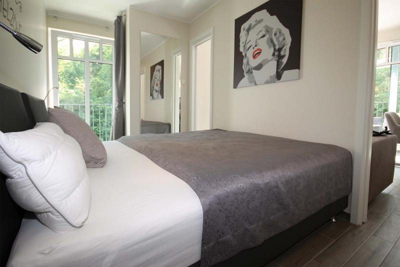 Schlafzimmer mit Bett, Wandbild und Balkonansicht
