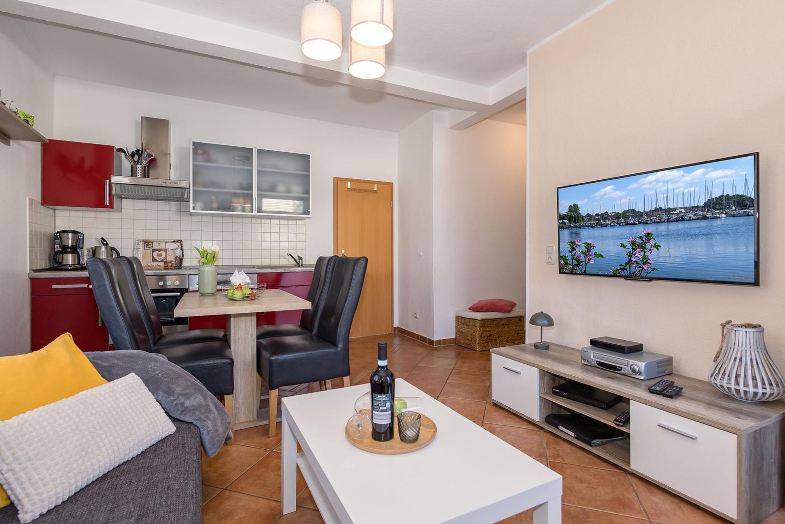 Wohn- und Essbereich mit Küche, Fernseher und Couch.