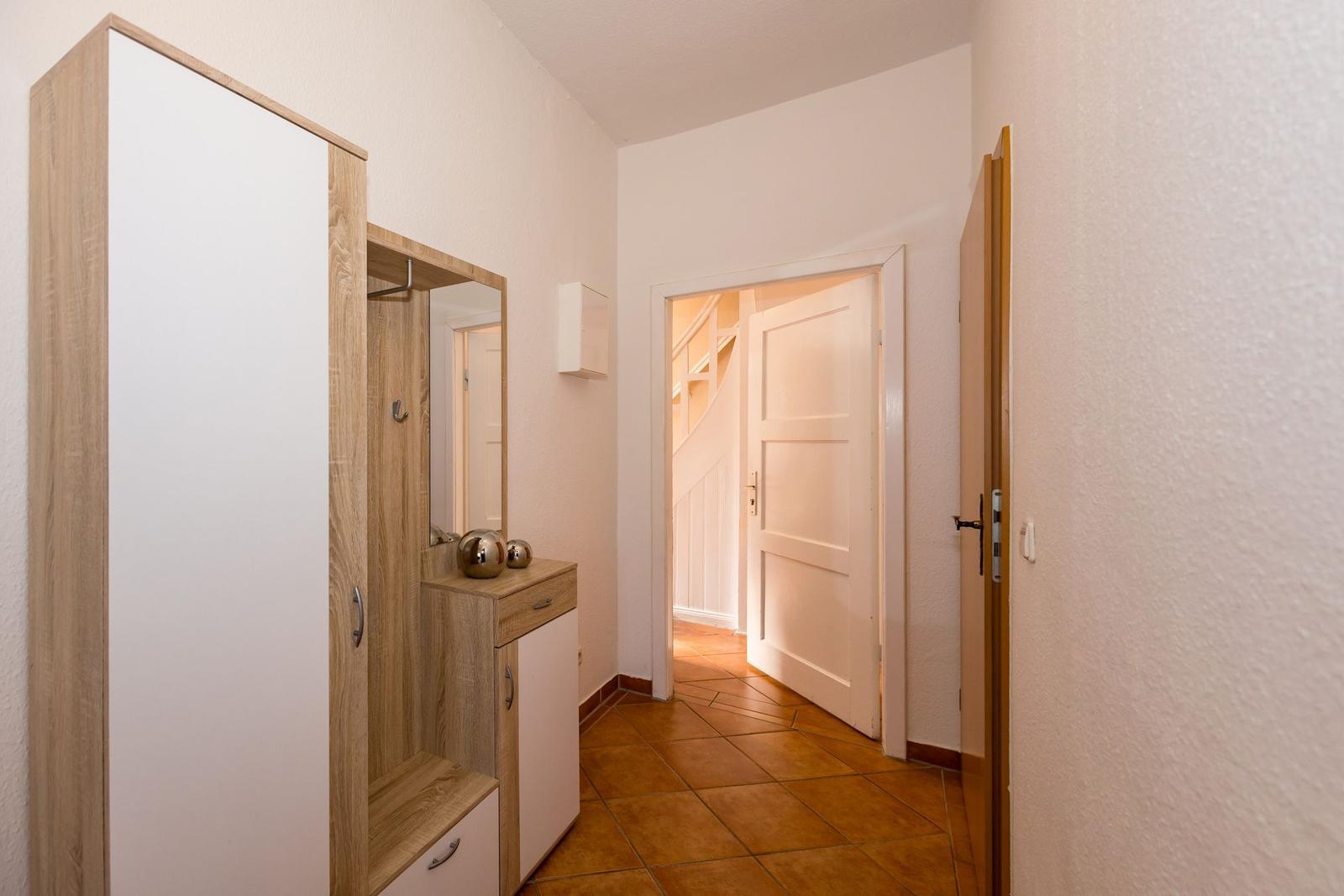 Flur mit Kleiderschrank, Spiegel und Tür zum Treppenhaus.