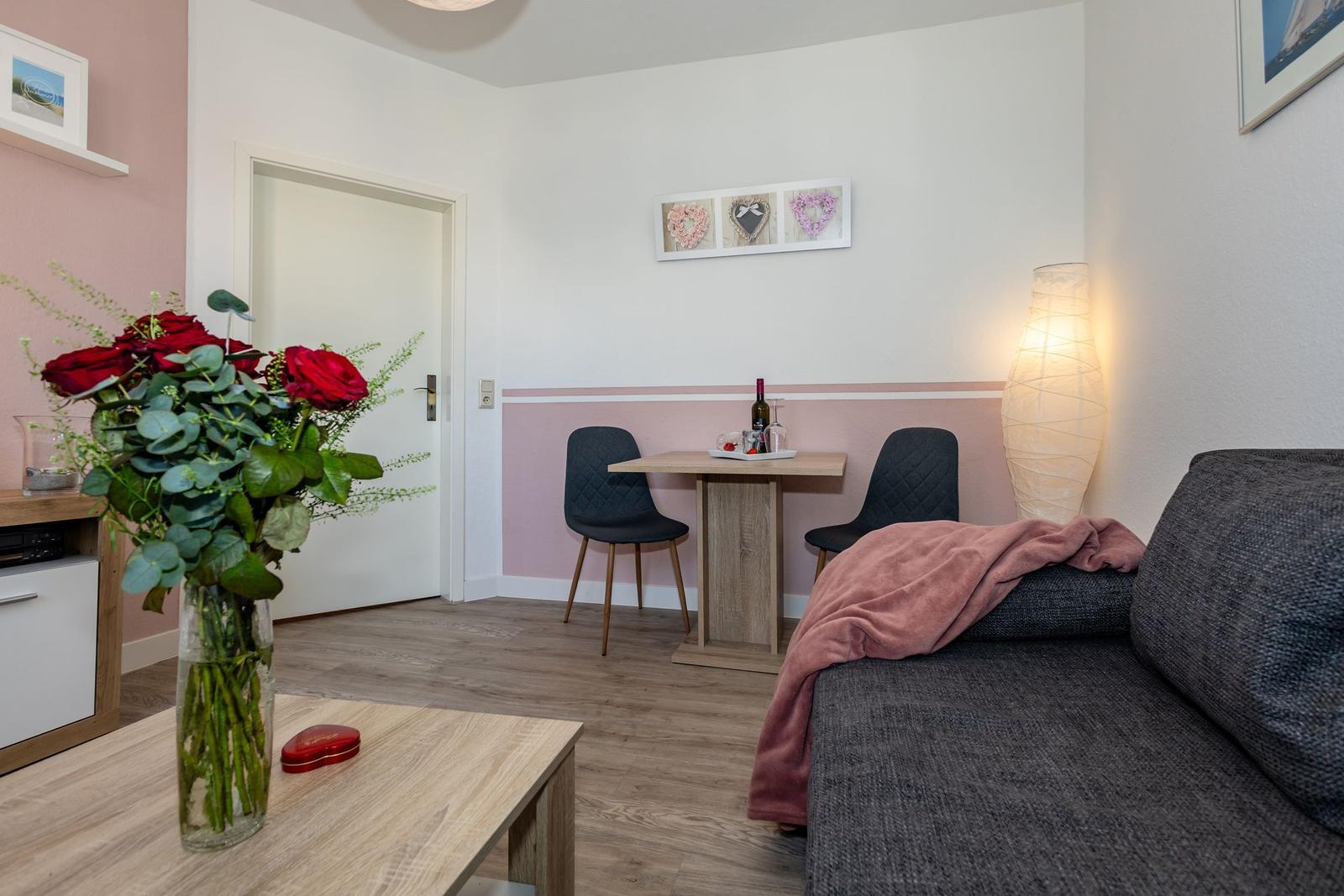 Wohnzimmer mit Sofa, Esstisch, Lampe und Blumen.