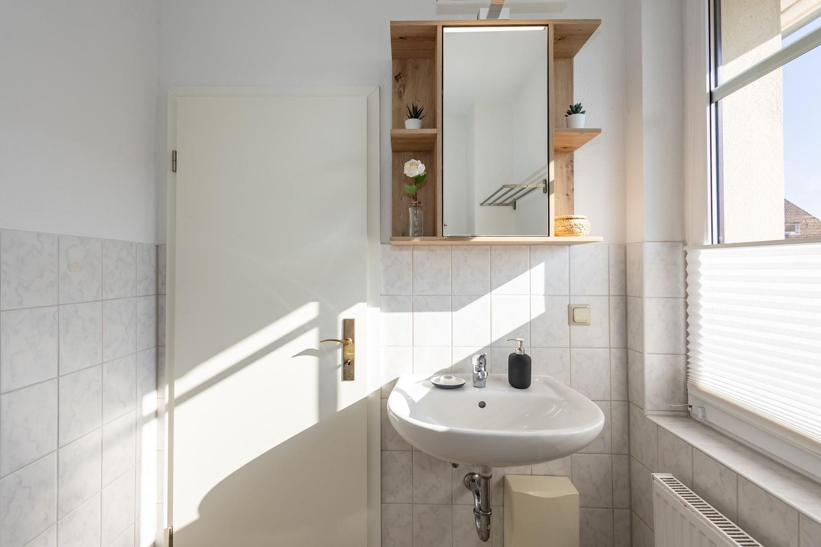 Badezimmer mit Waschbecken, Spiegelschrank und Fenster
