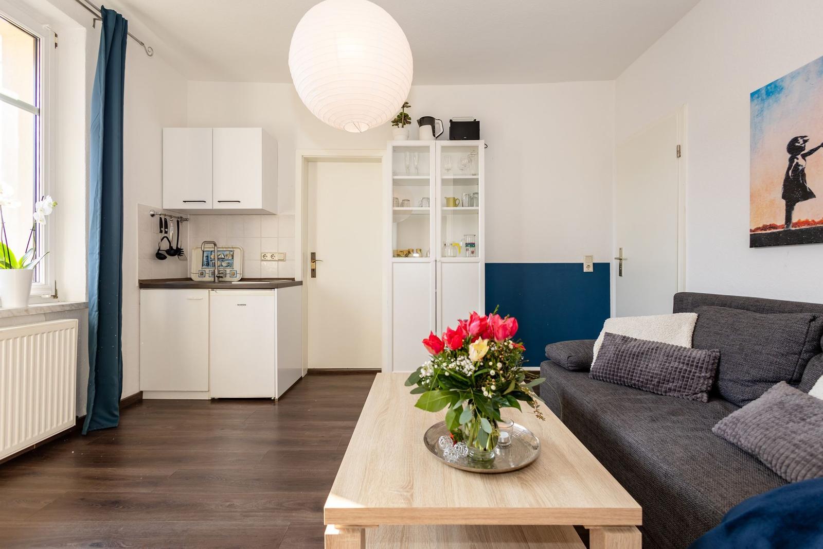 Wohnbereich mit Sofa, Esstisch und kleiner Küche.