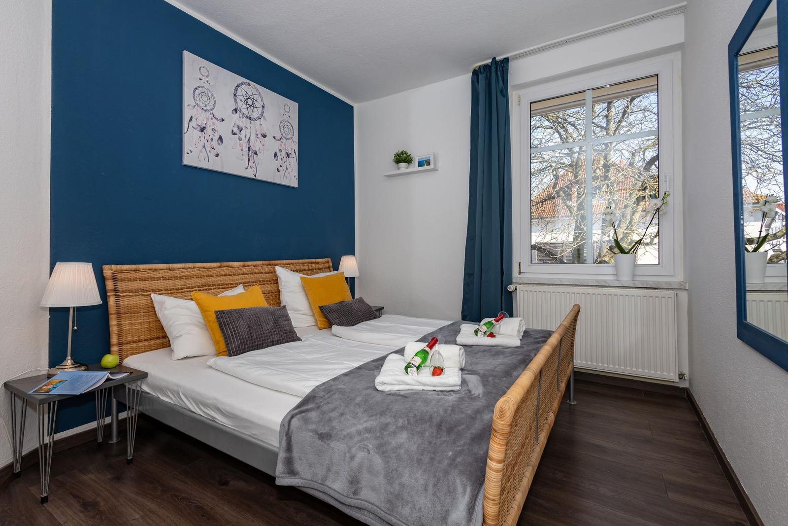 Schlafzimmer mit Bett, Wandbild und Fenster mit Blick.
