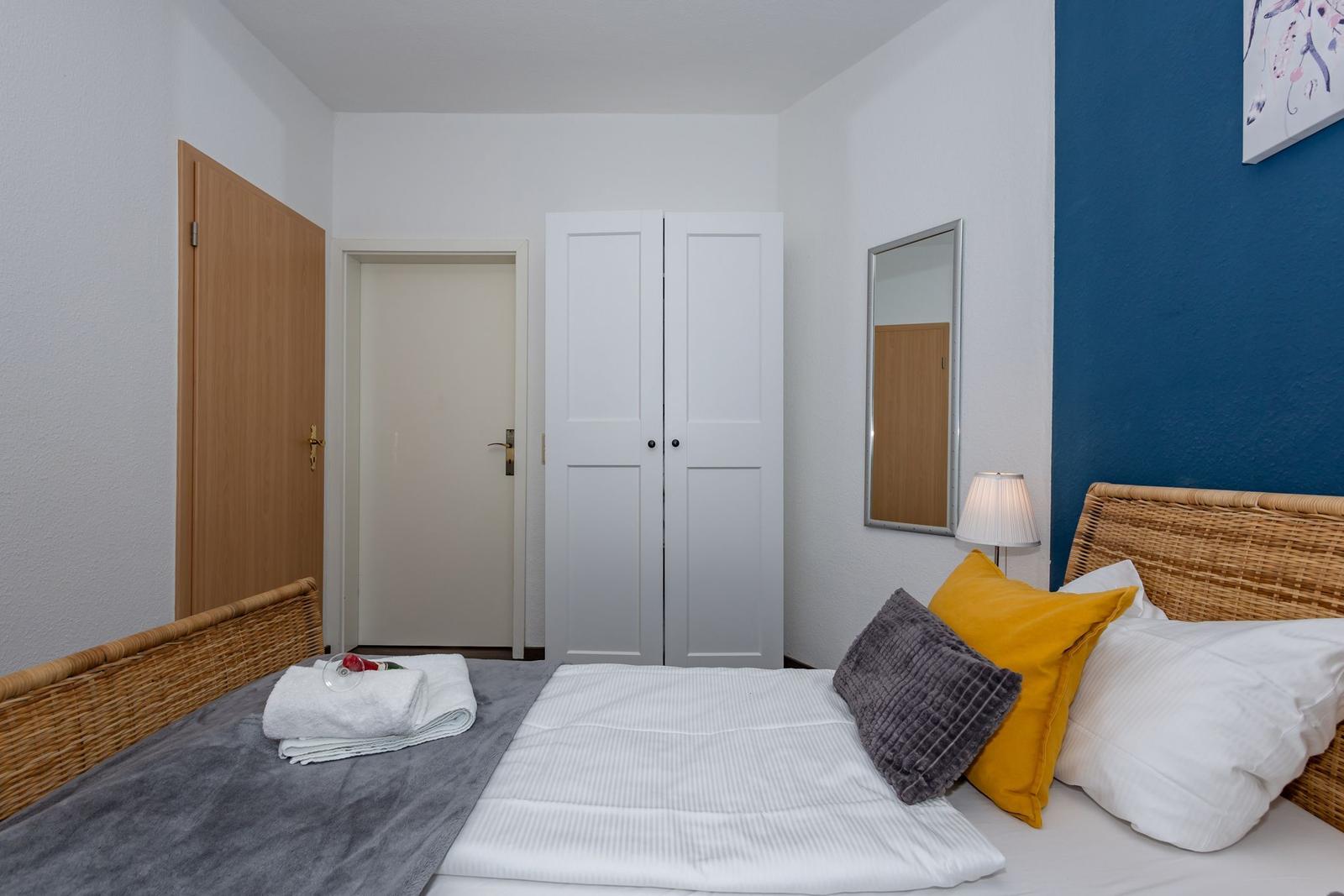 Schlafzimmer mit Bett, Kleiderschrank und Spiegel an der Wand.