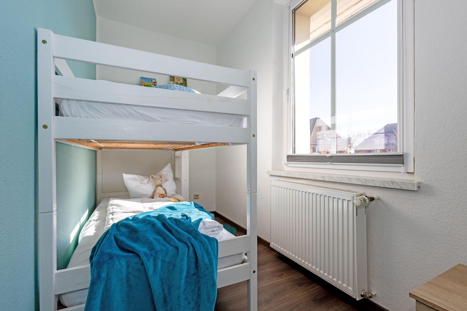 Zimmer mit Doppelstockbett, Fenster und Heizkörper.