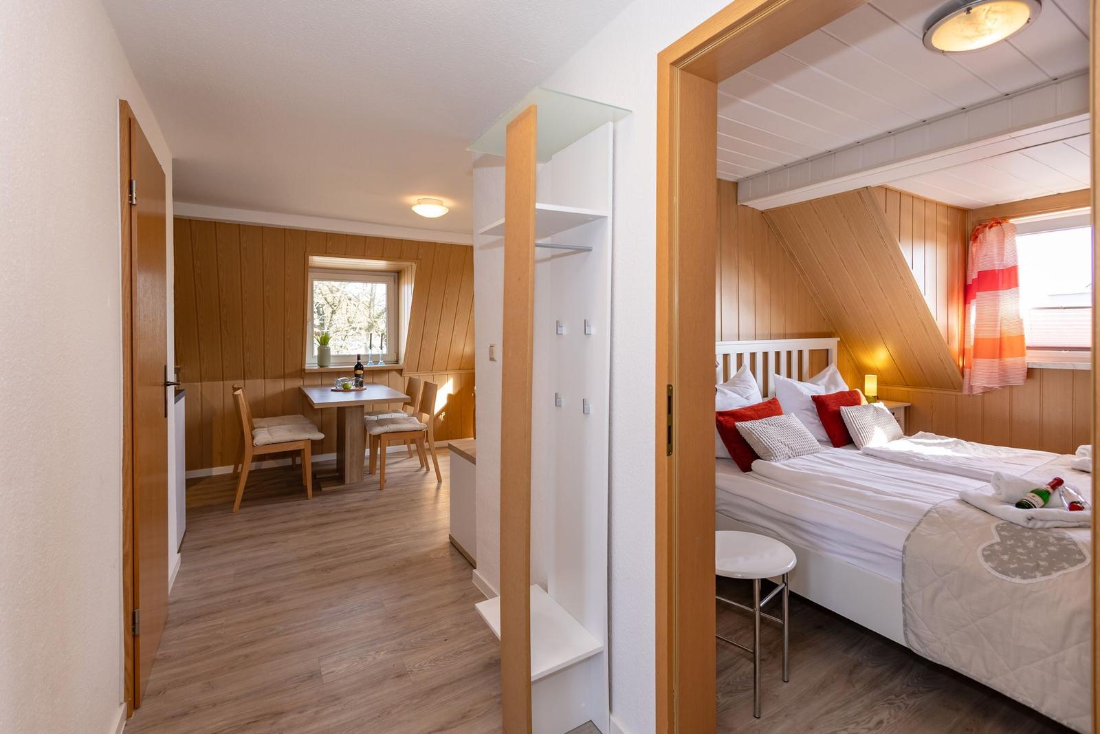 Schlafzimmer mit Doppelbett und angrenzender Essnische mit Tisch und Stühlen.
