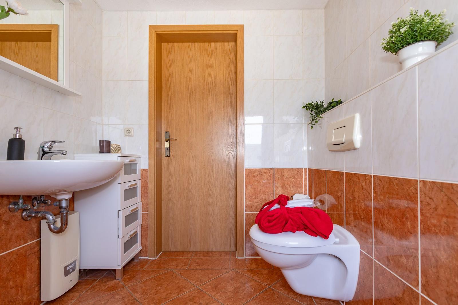 Badezimmer mit Waschbecken, Toilette und Pflanzen an der Wand.