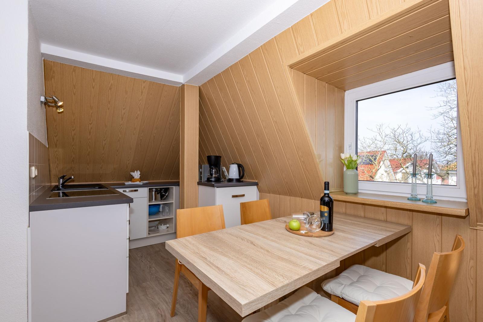 Küche mit Essplatz unter Dachschräge, Holzwand, Fenster mit Blick.