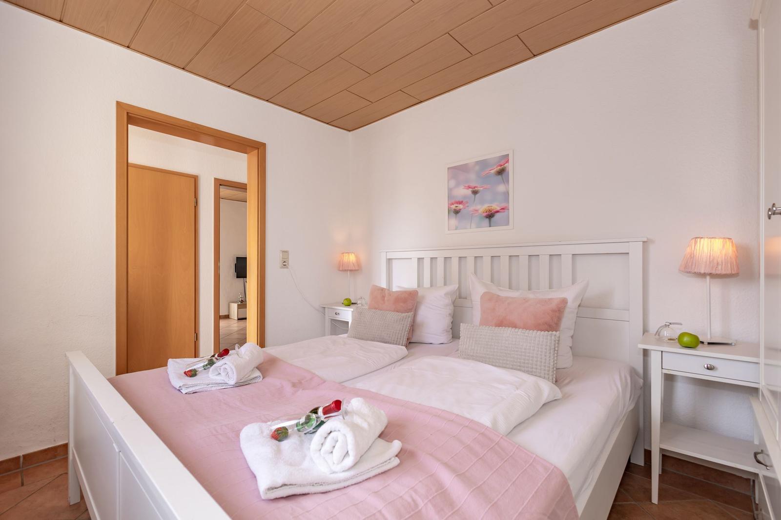 Schlafzimmer mit Bett, Nachttisch und Bild an der Wand.