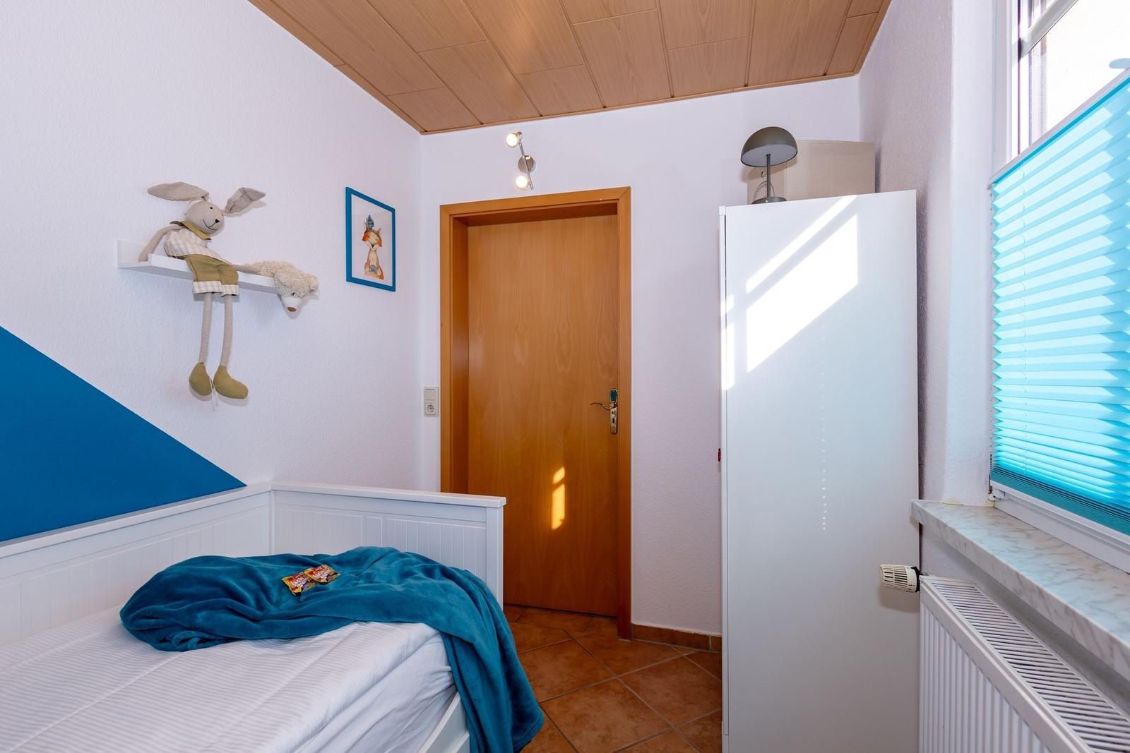 Ein Schlafzimmer mit Bett, Kleiderschrank und Fenster mit Jalousie.