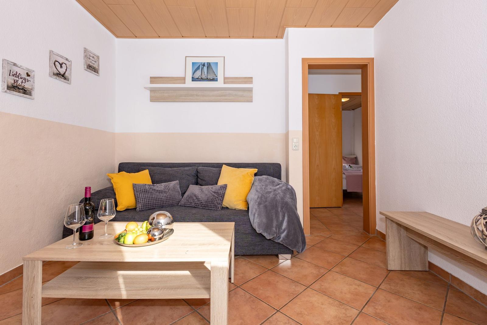 Wohnzimmer mit Sofa, Couchtisch und Blick in Schlafzimmer