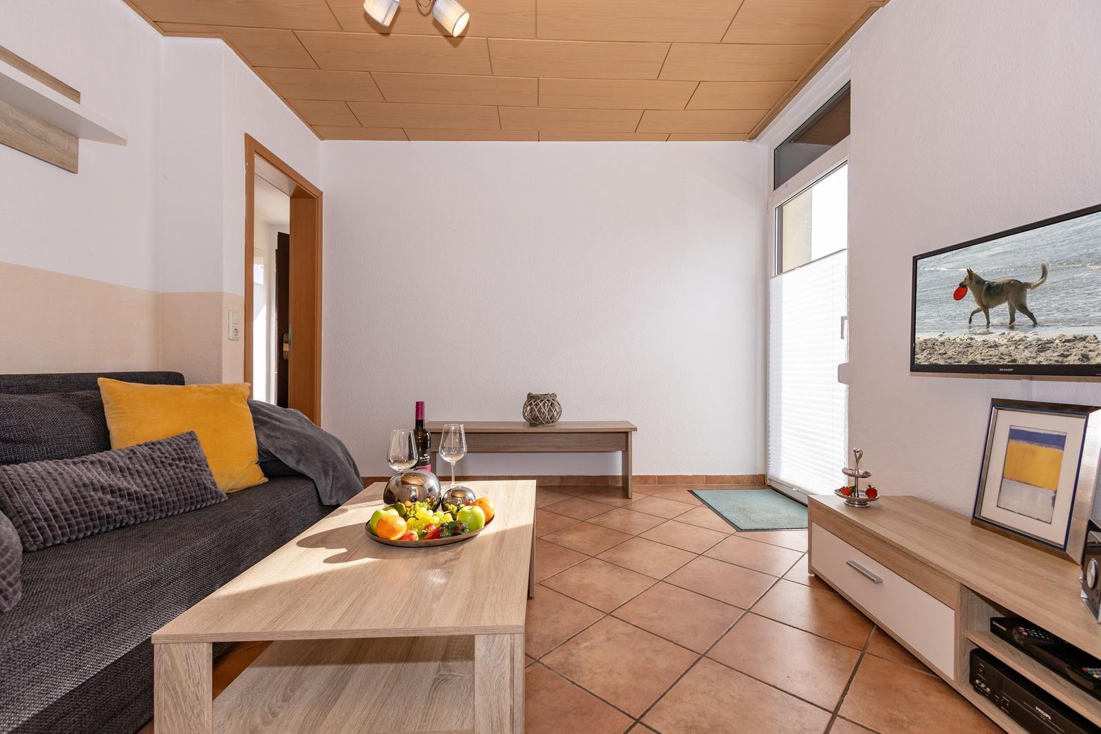 Wohnzimmer mit Sofa, Couchtisch und Fernseher an der Wand.