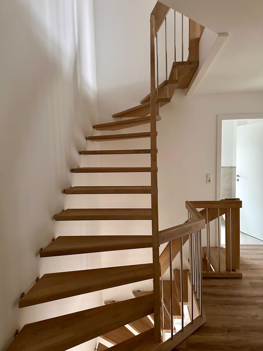 Holztreppe mit Metallgeländer führt zur oberen Etage.