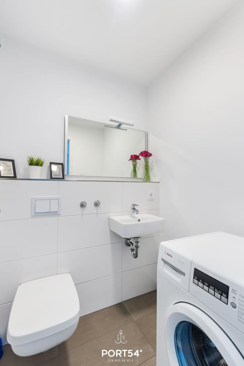 Badezimmer mit Toilette, Waschbecken und Waschmaschine.