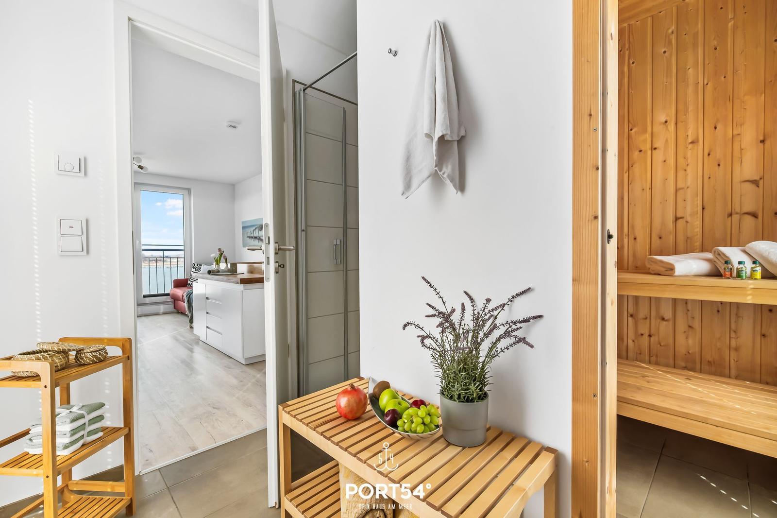 Sauna mit Holzbank und Handtüchern. Blick in Wohnbereich mit Balkon.