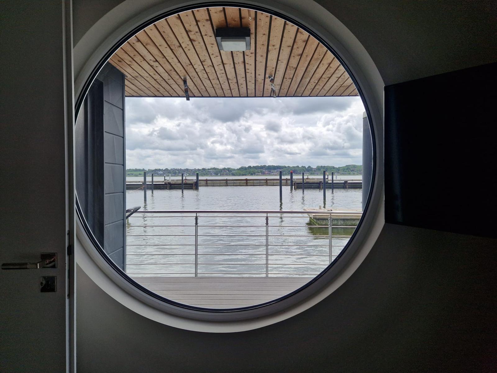 Rundes Fenster mit Blick auf Wasser und Steg
