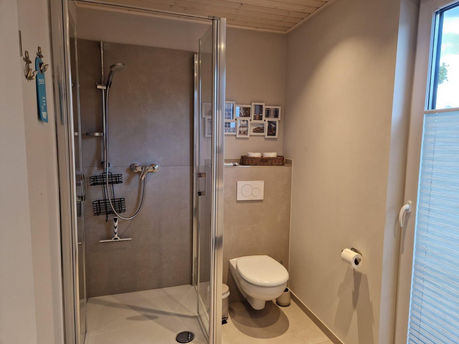 Bad mit Dusche, Toilette und Fenster mit Jalousie.