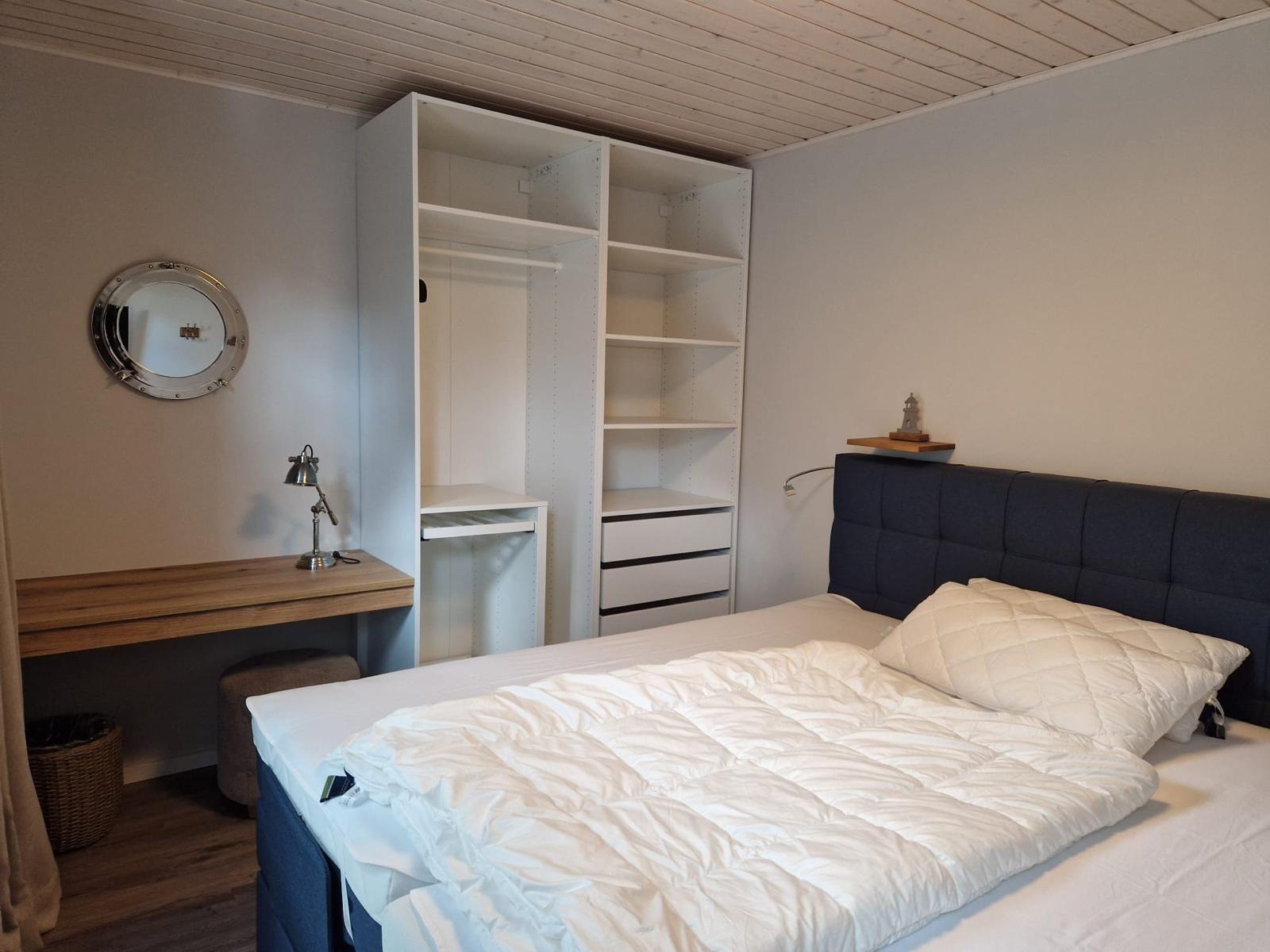 Schlafzimmer mit Bett, Kleiderschrank und Schreibtisch.