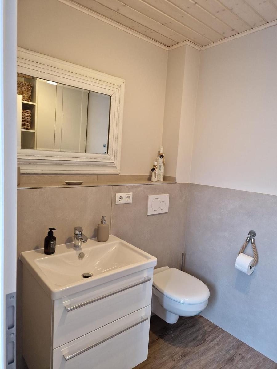 Badezimmer mit Waschbecken, Spiegel und Toilette
