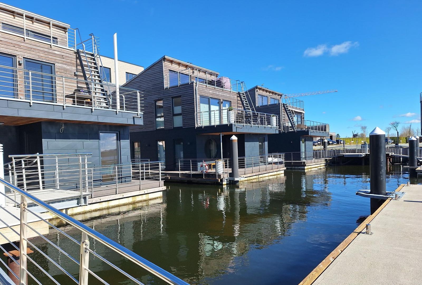 Moderne Bootsanlegerhäuser am Wasser mit Balkonen und Metallgeländern.
