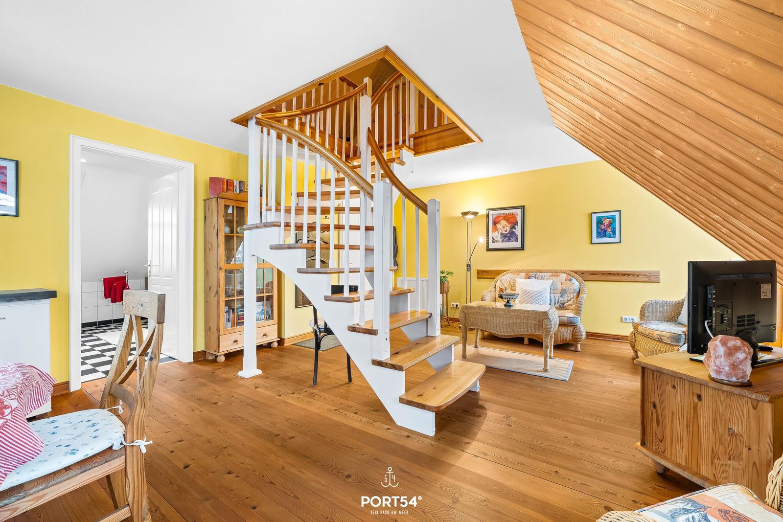 Wohnbereich mit Holztreppe, gelben Wänden und Wohnmöbeln.