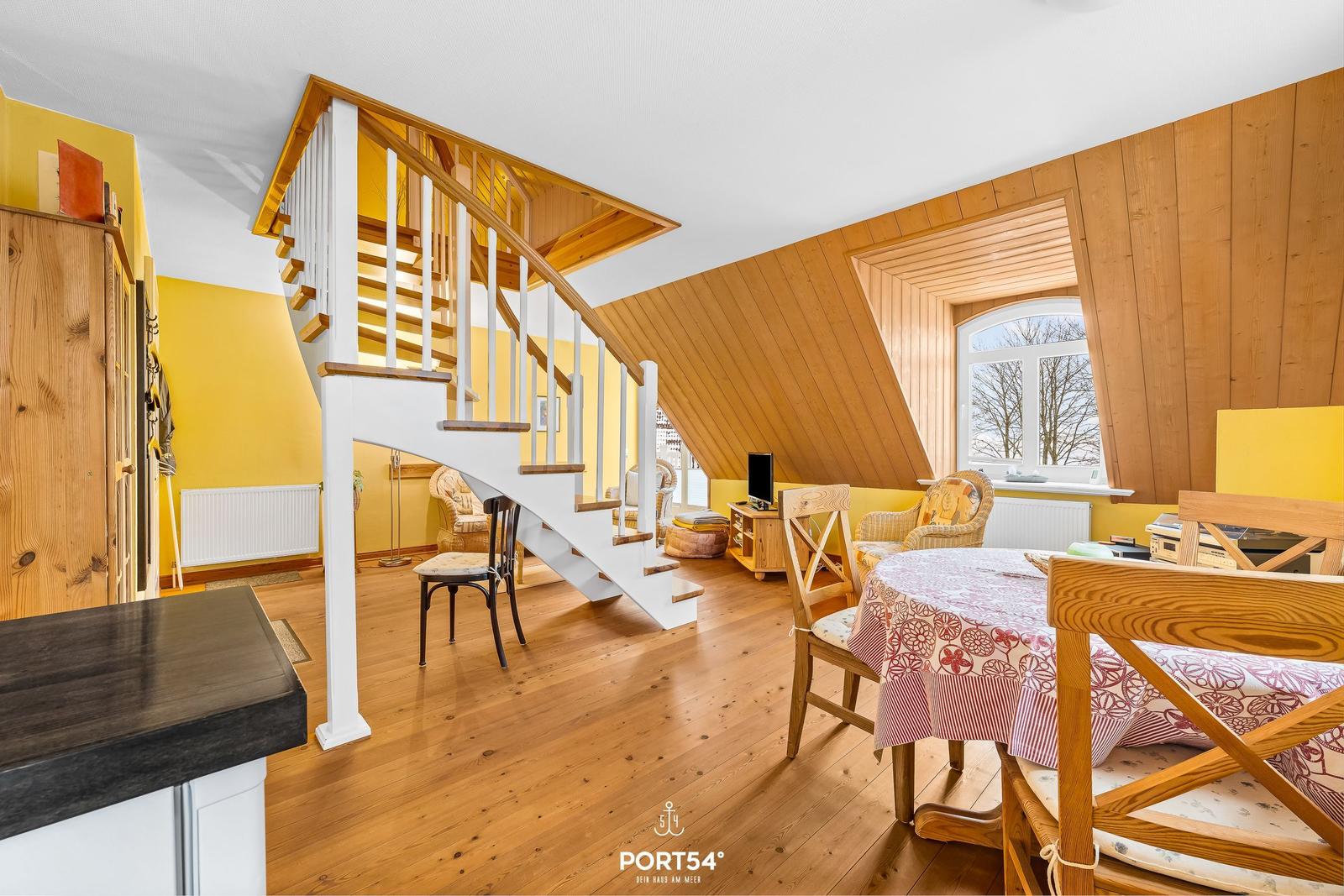 Haus mit Holzverkleidung, Treppe und Essbereich mit Tisch und Stühlen.