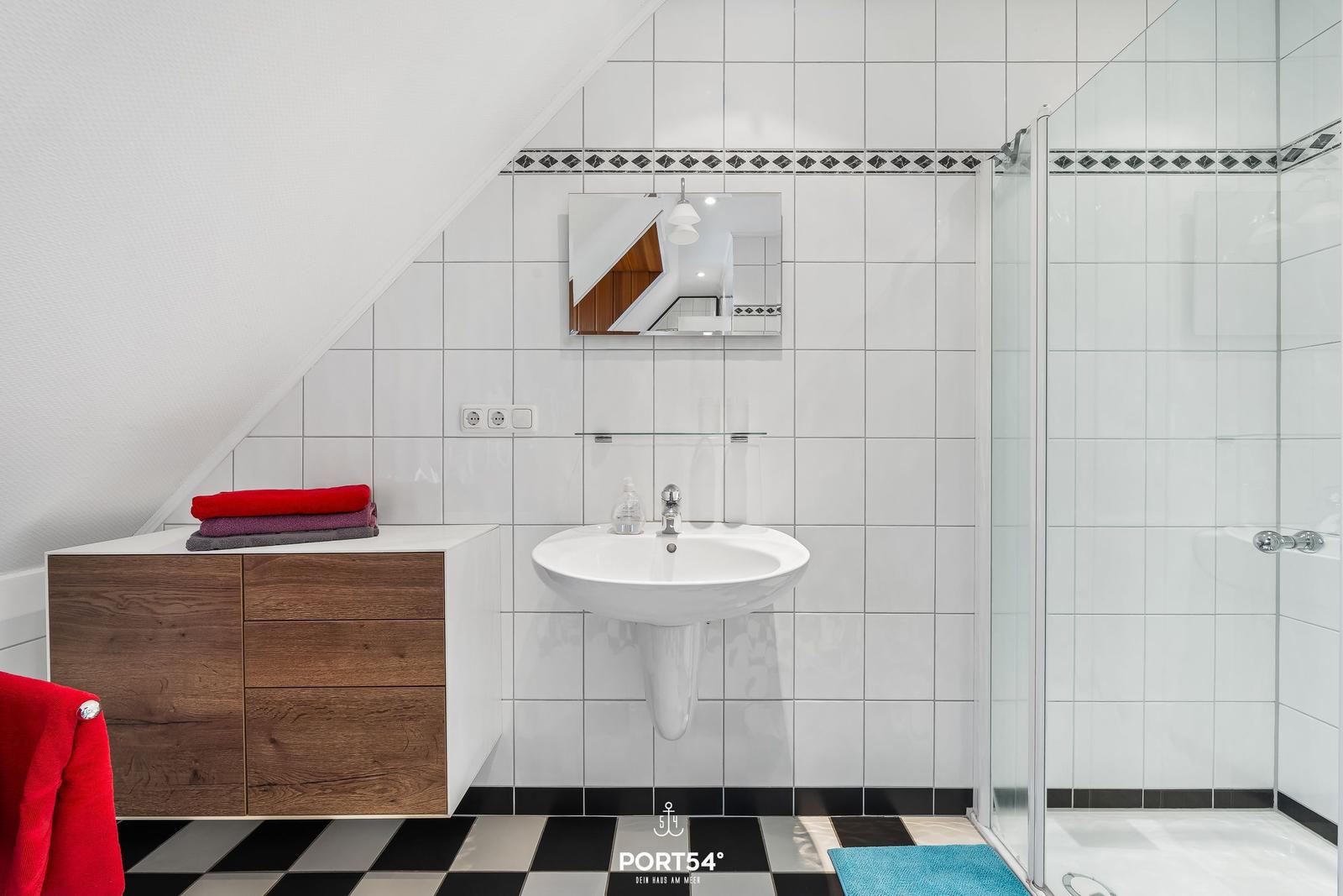 Badezimmer mit Dusche, Waschbecken und Holzschrank unter Dachschrägen