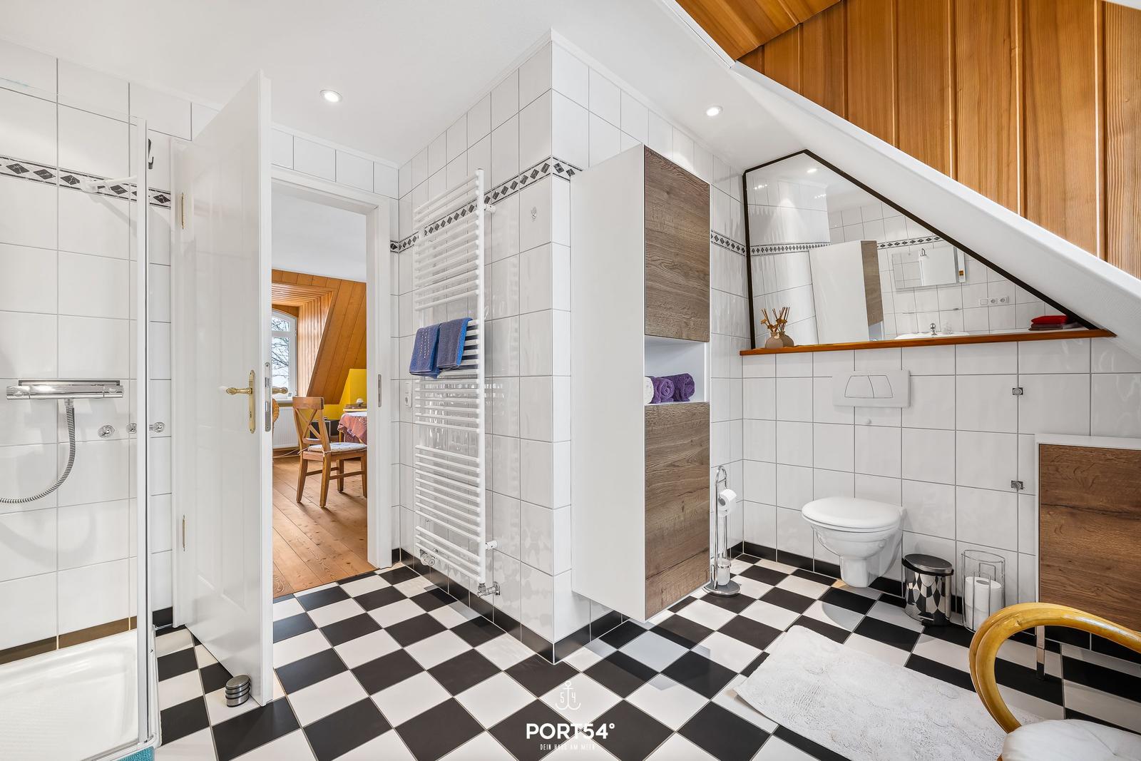 Badezimmer mit Dusche, Toilette und Spiegelschrank unter Dachschrägen.