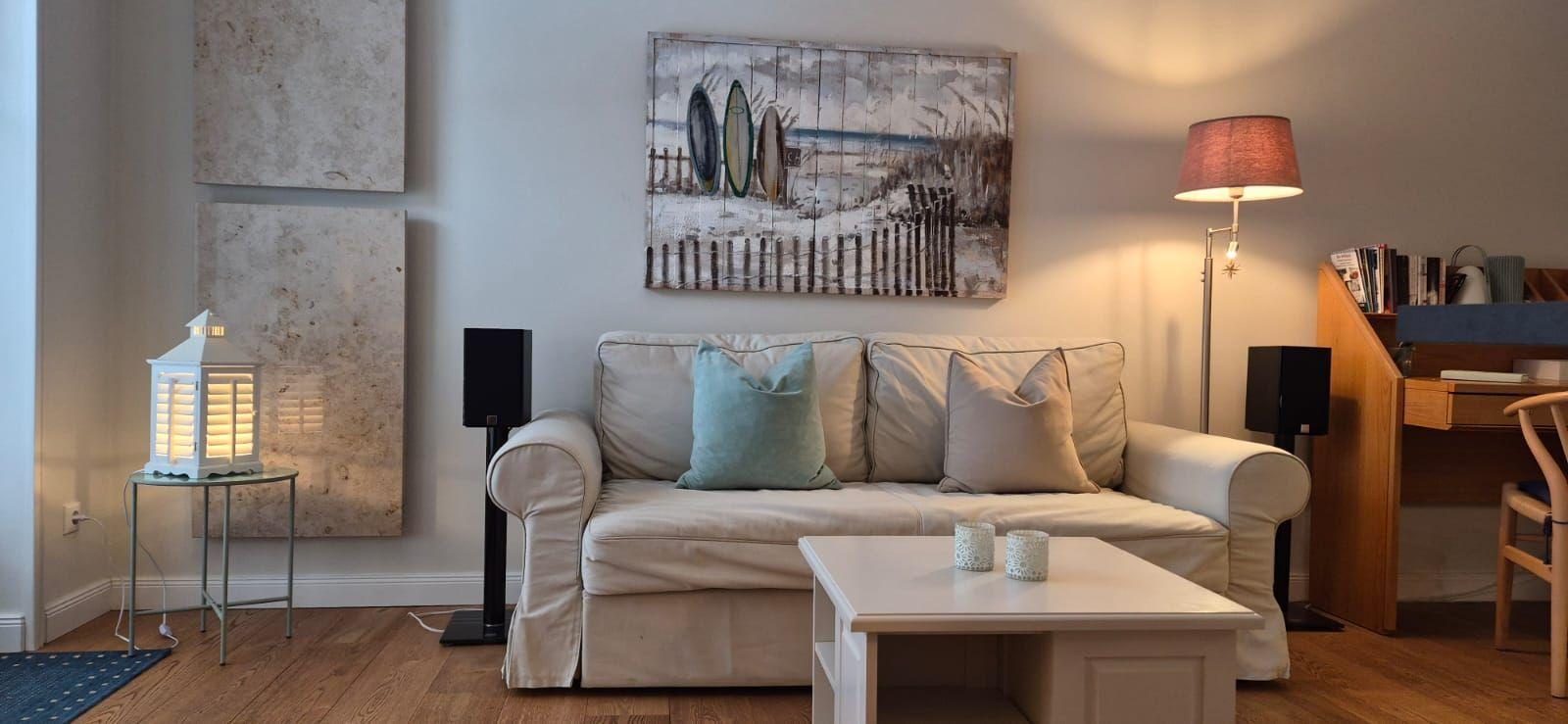 Wohnzimmer mit Sofa, Couchtisch und Wandbild mit Surfbrettern.