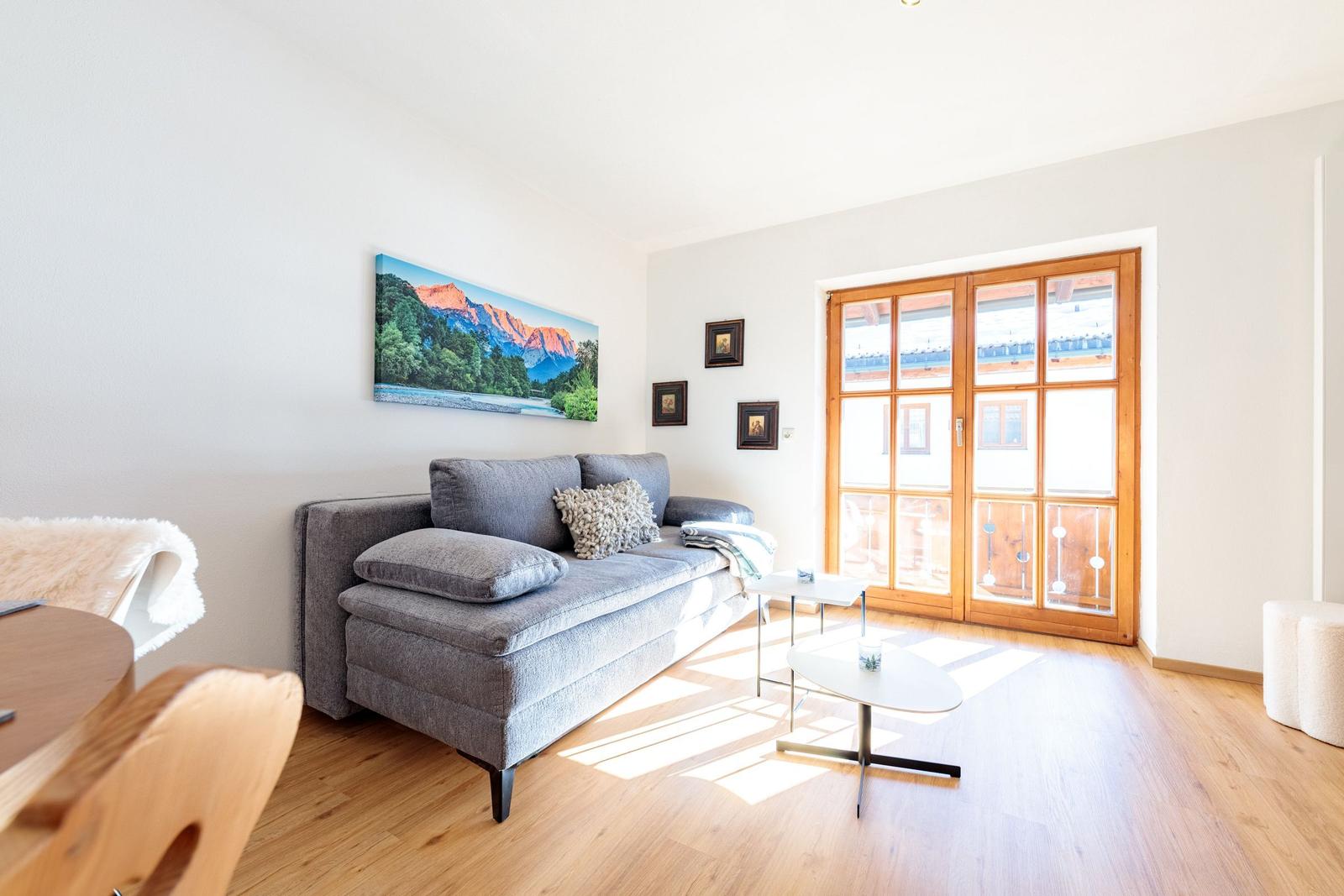 Wohnzimmer mit Sofa, Tischen und Fenster zur Terrasse.