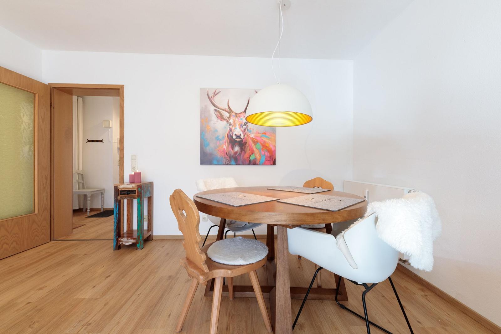 Essbereich mit runden Tisch, Stühlen und Wandbild eines Hirsches.