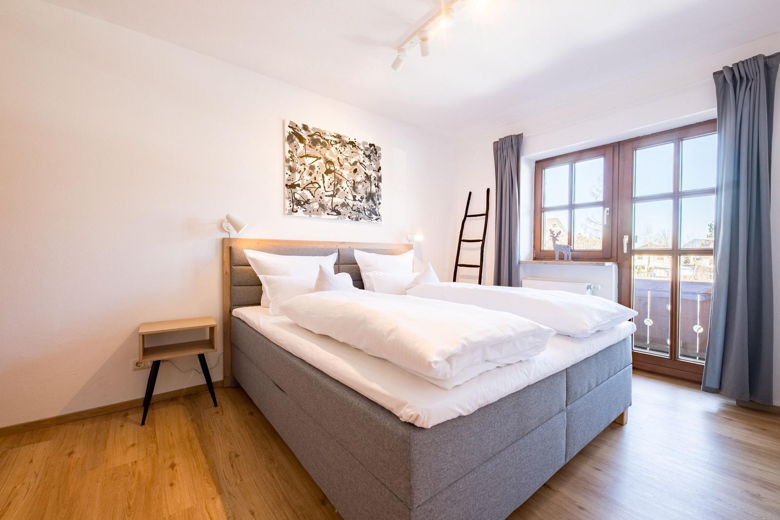 Schlafzimmer mit Doppelbett, Holzboden und Fenster mit Blick.