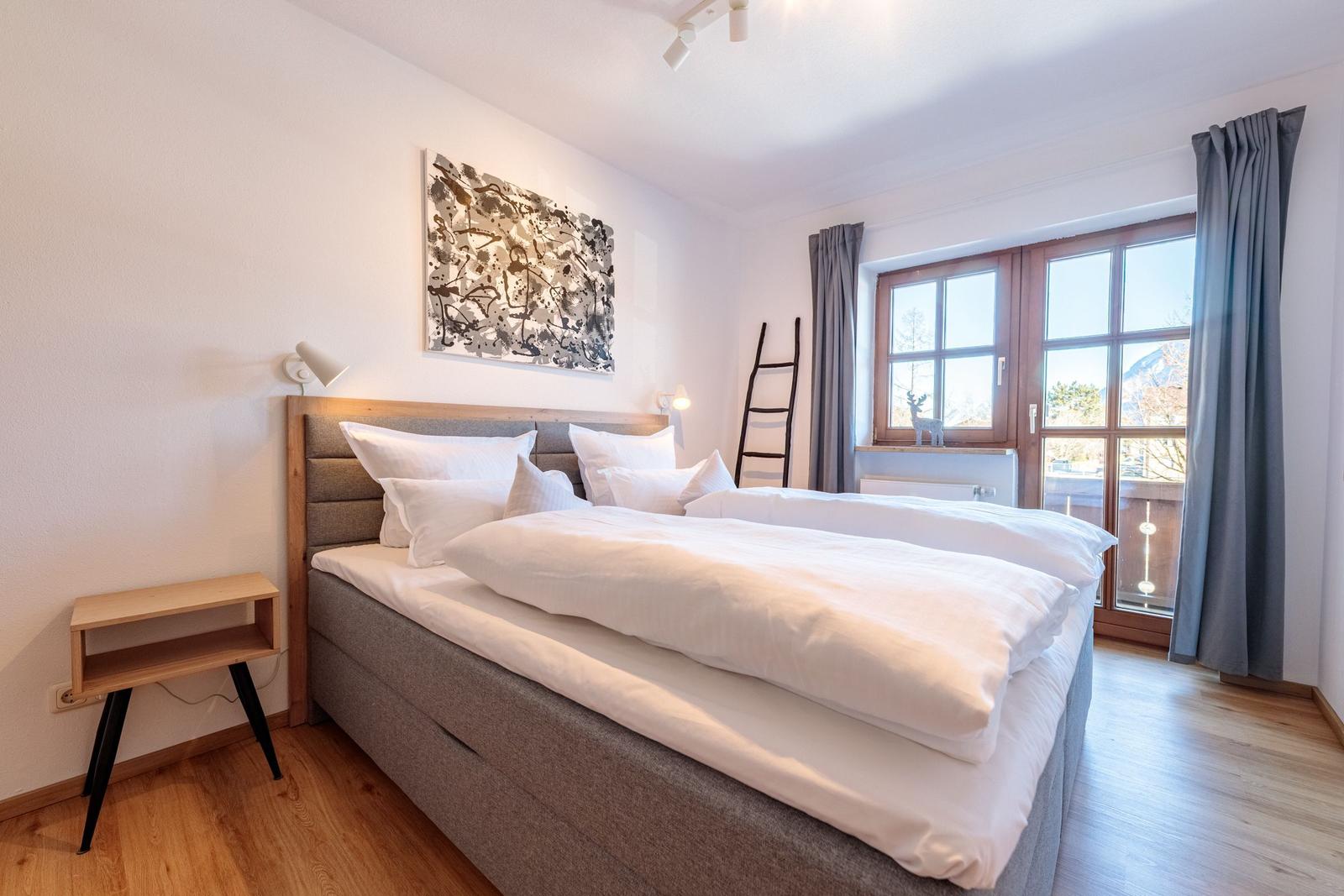 Schlafzimmer mit Doppelbett, Holzboden und Fenster mit Blick.