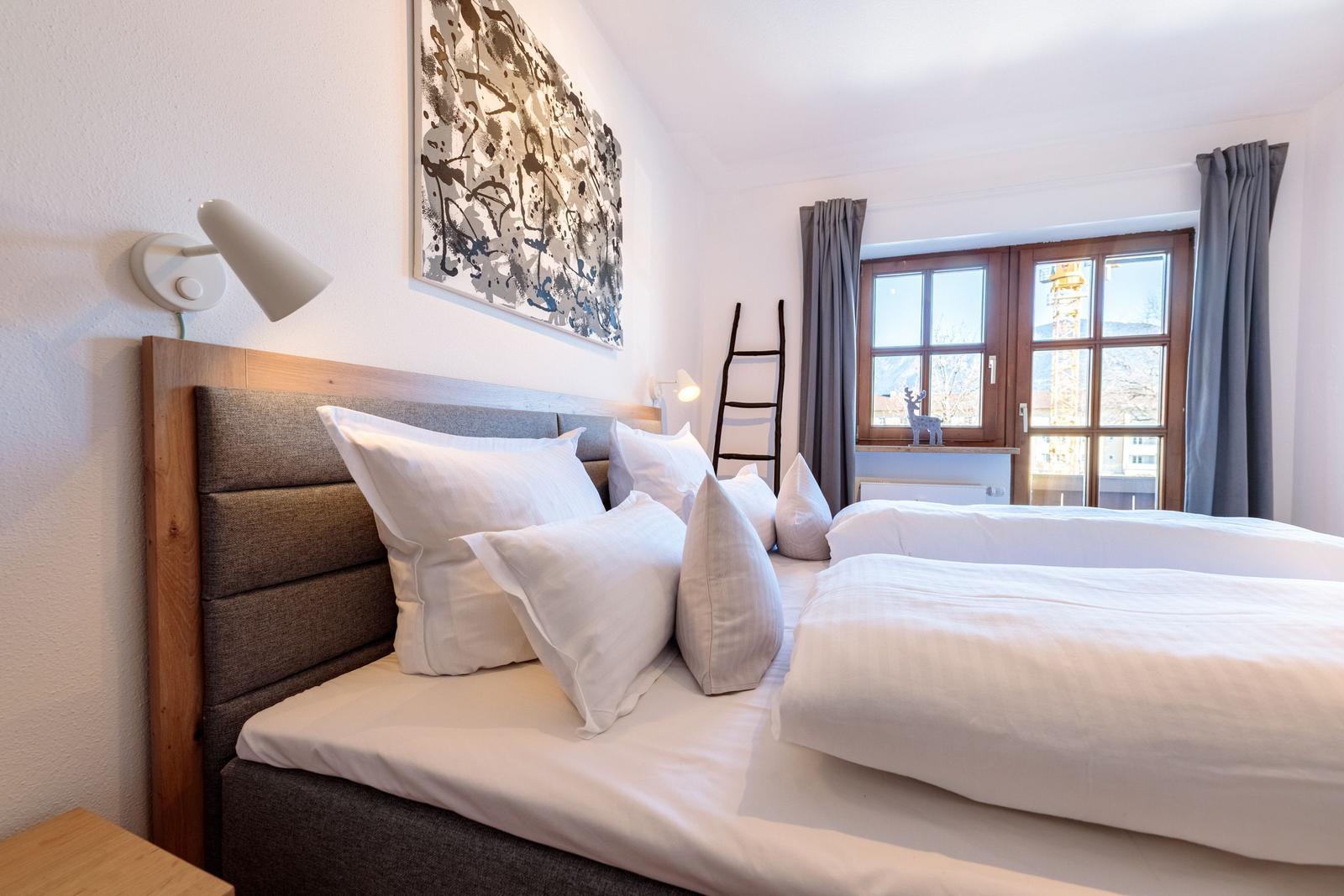 Schlafzimmer mit Bett, Fenster und Wandbild.