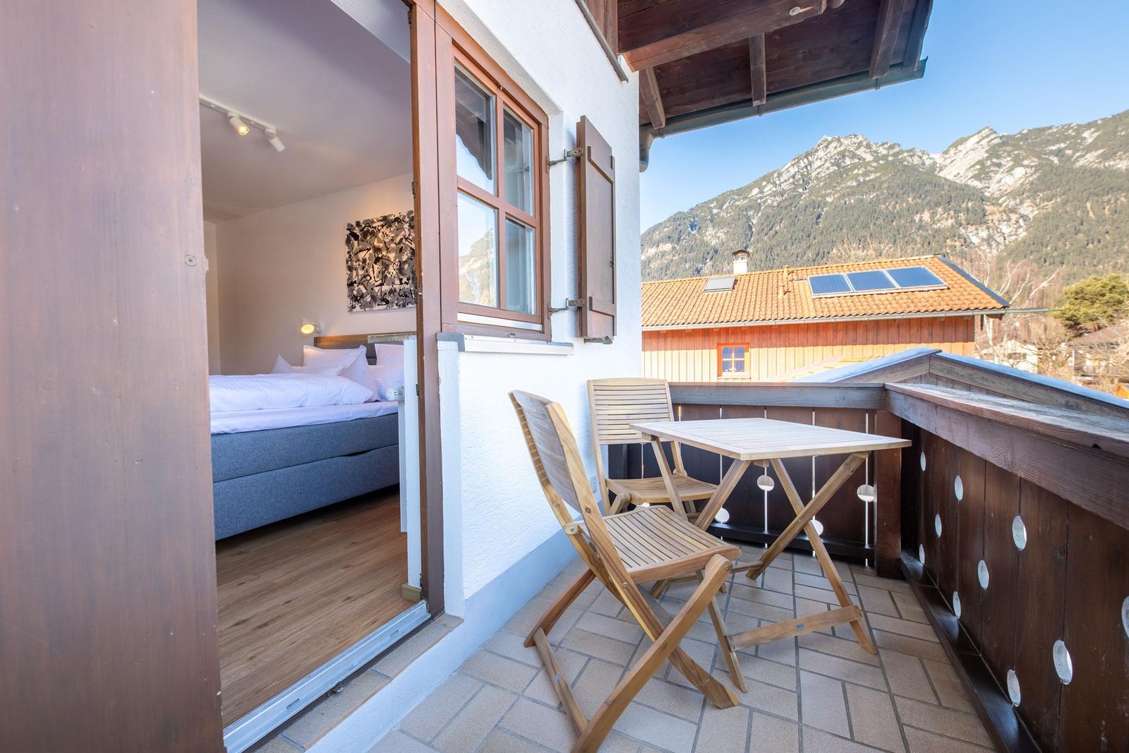 Terrasse mit Tisch und Stühlen. Blick auf Berge und Haus mit Solaranlage.