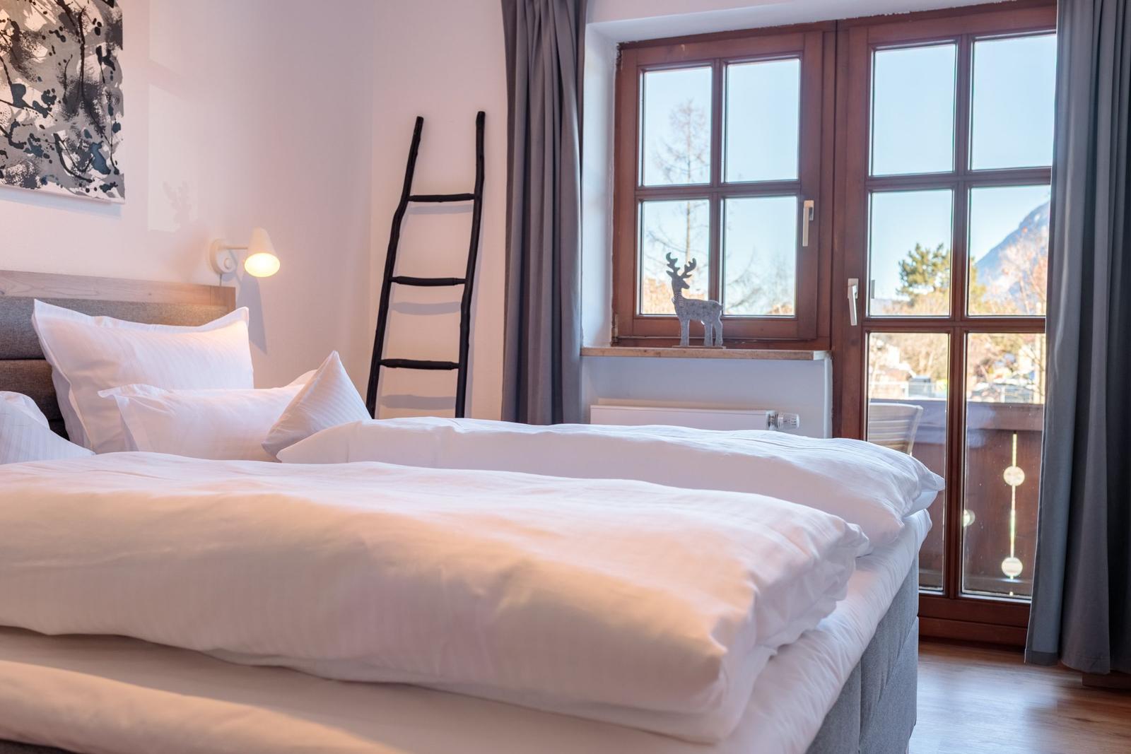 Ein Schlafzimmer mit Doppelbett, Fenster und dekorativen Elementen.