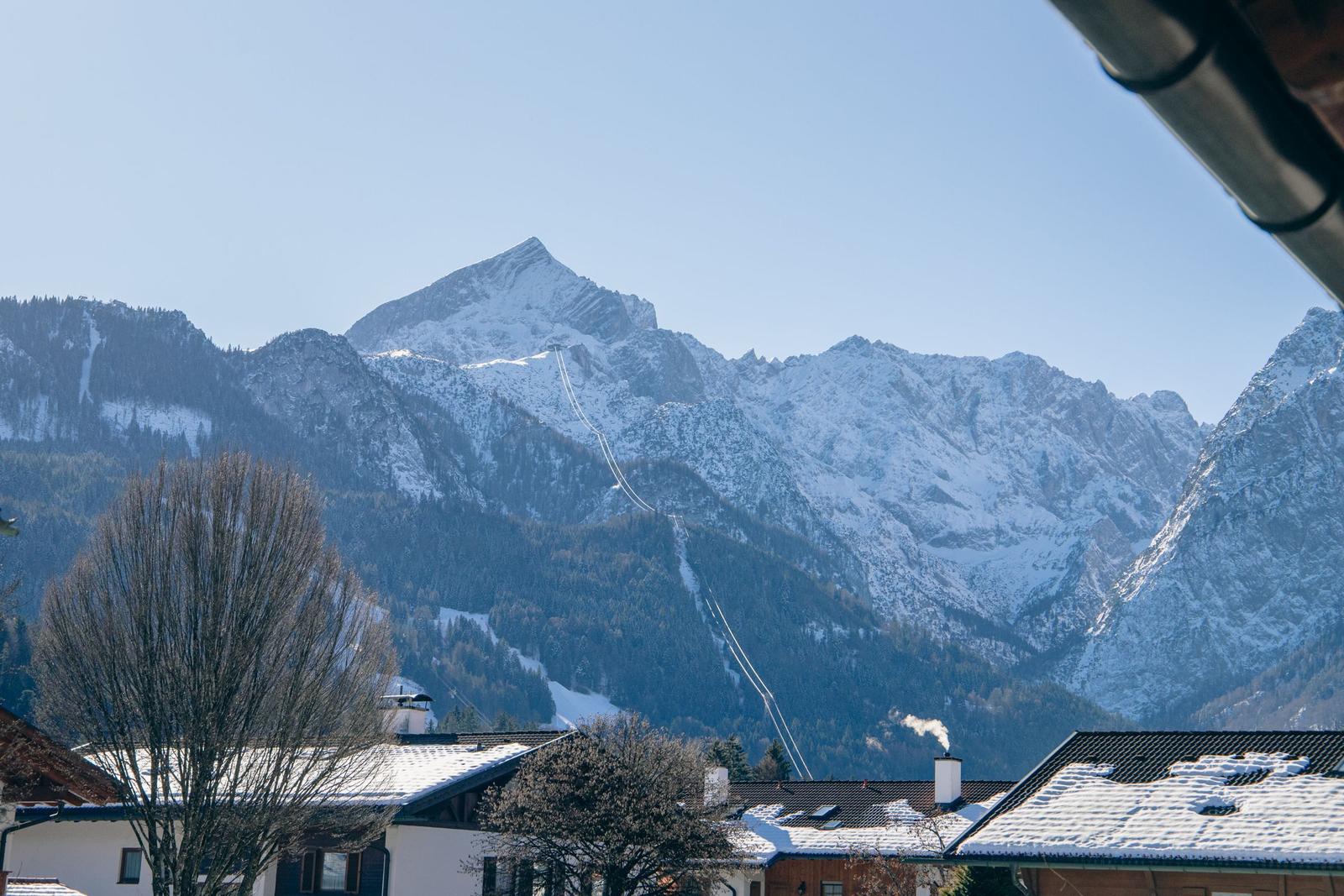 Schneekappen bedecken die Berge. Schnee liegt auf Dächern und Bäumen.