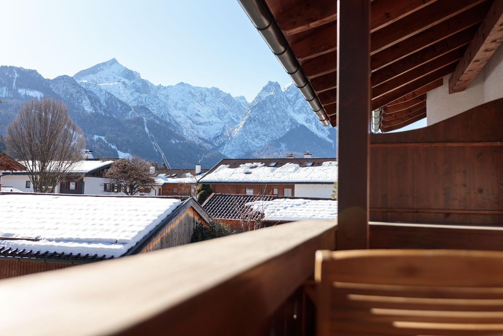 Balkon mit Blick auf schneebedeckte Berge und Dächer