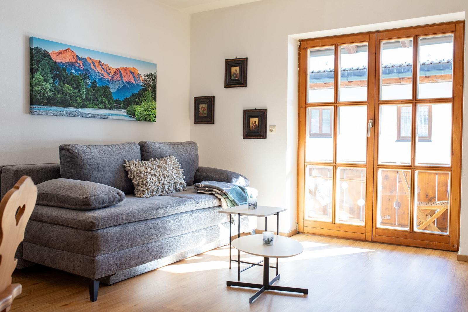 Wohnzimmer mit Sofa, Tischen und Blick auf Balkon