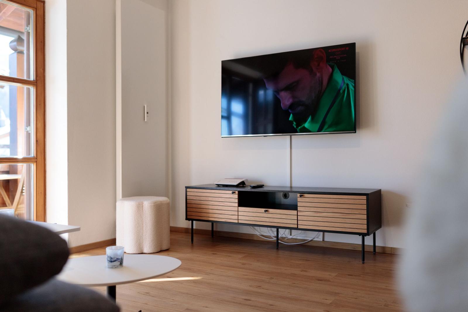 Wohnzimmer mit Fernseher, Holzboden und modernem Sideboard.