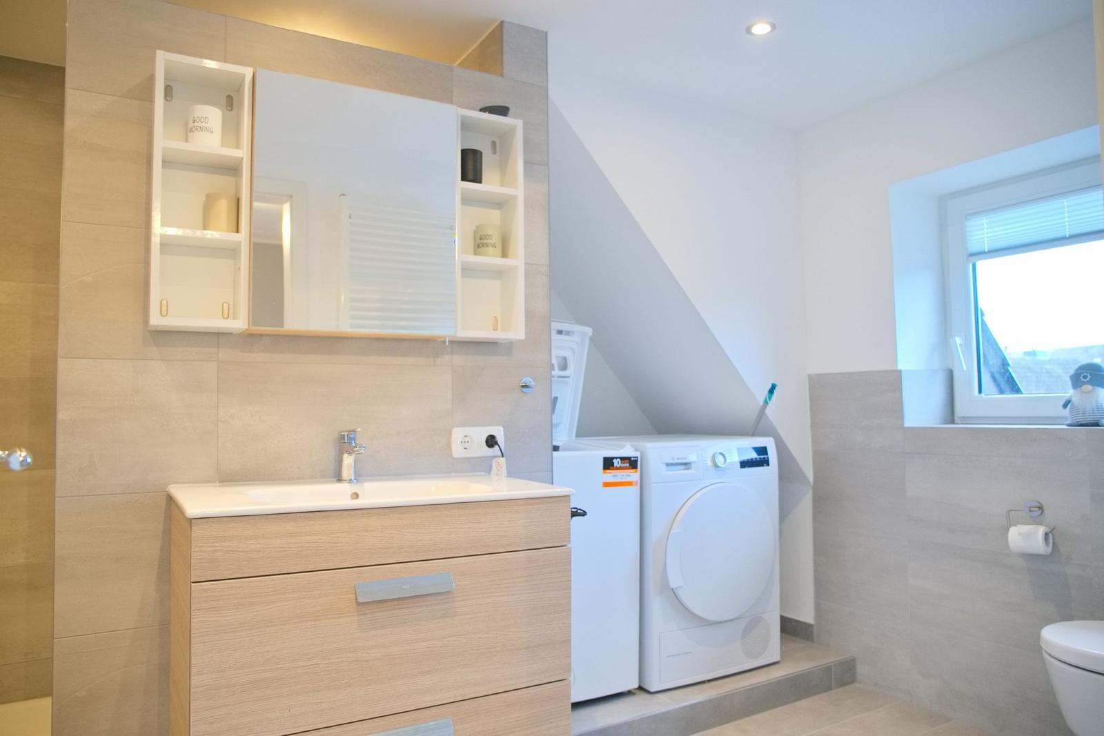 Badezimmer mit Waschmaschine und Spiegelschrank
