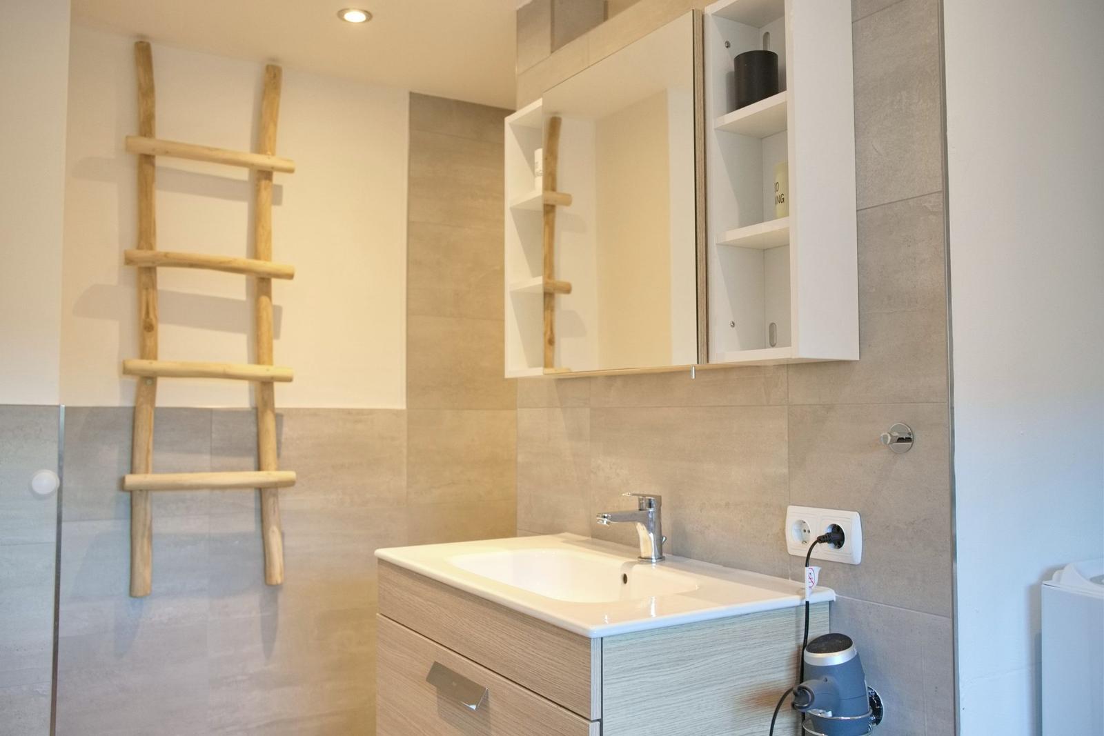 Bad mit Waschbecken, Spiegelschrank und Holzhandtuchhalter.