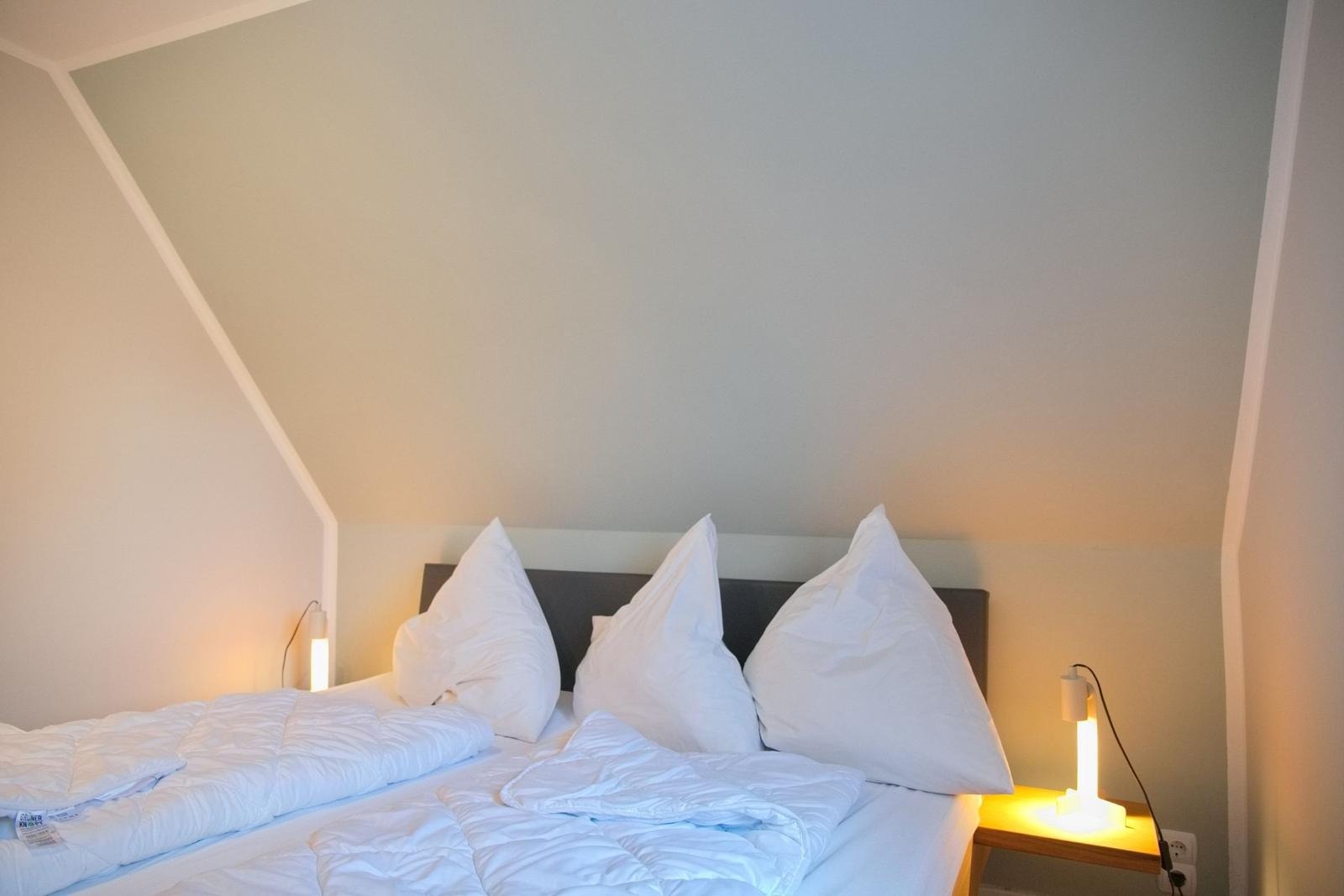 Schlafzimmer mit Doppelbett, weißen Kissen und Nachttischlampen.