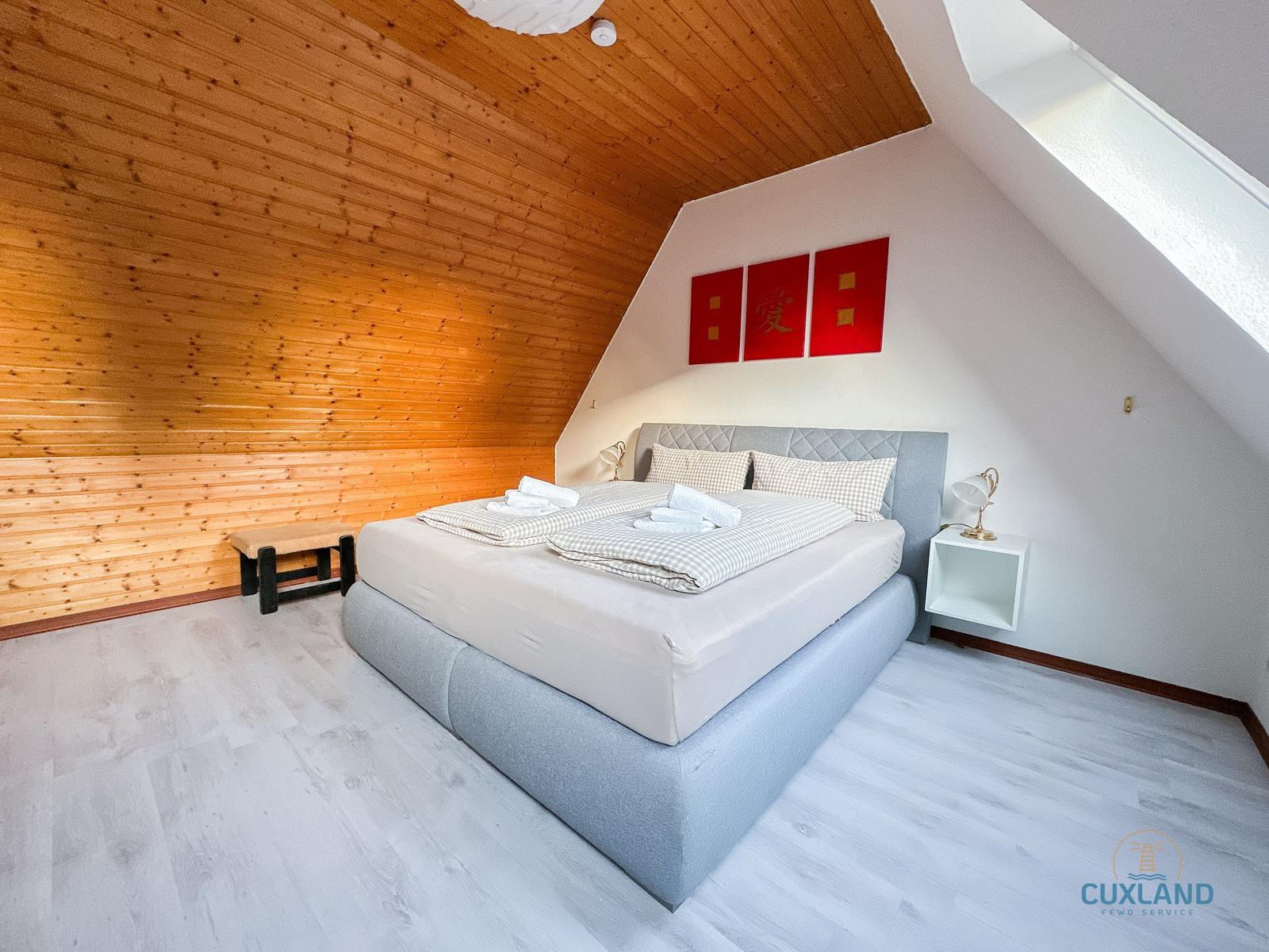 Schlafzimmer mit Holzwand, Bett und Fenster