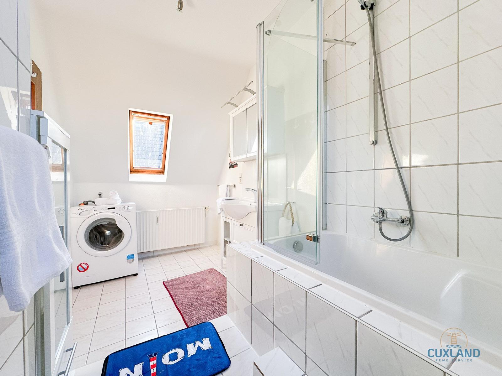 Badezimmer mit Dusche, Waschmaschine und Fenster.