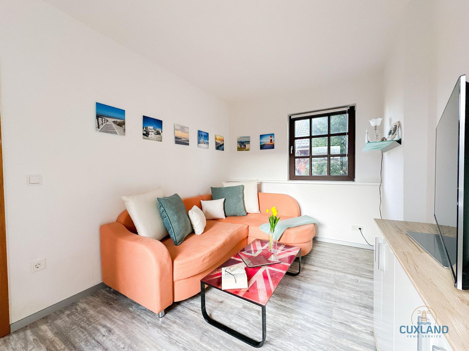 Wohnzimmer mit orangefarbenem Sofa, Couchtisch und Fenster.