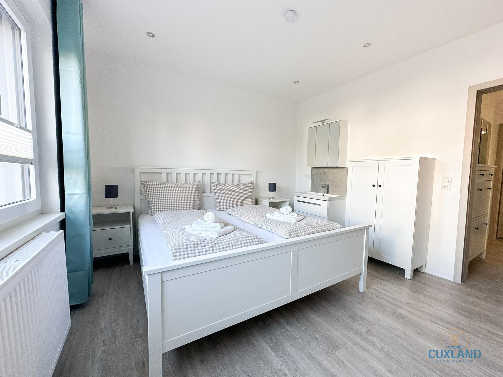 Schlafzimmer mit Doppelbett, Schrank und Fenster