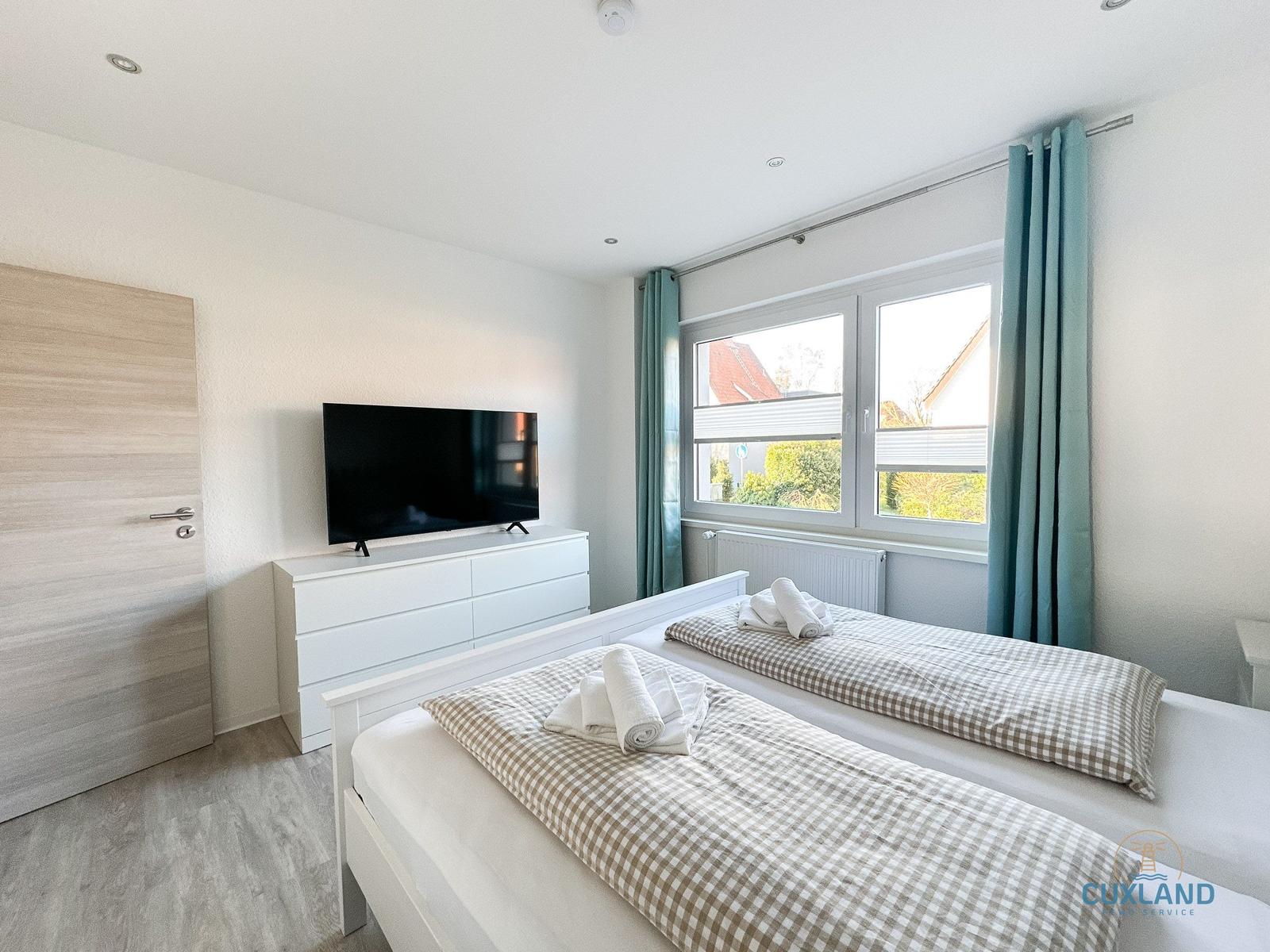 Schlafzimmer mit Doppelbett, TV und Fenster mit Blick.