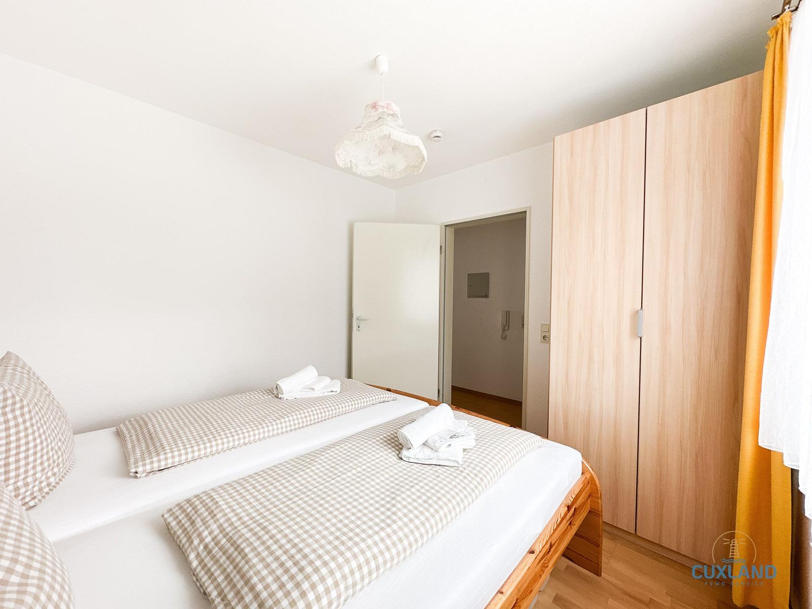 Schlafzimmer mit Bett, Kleiderschrank und Decke.